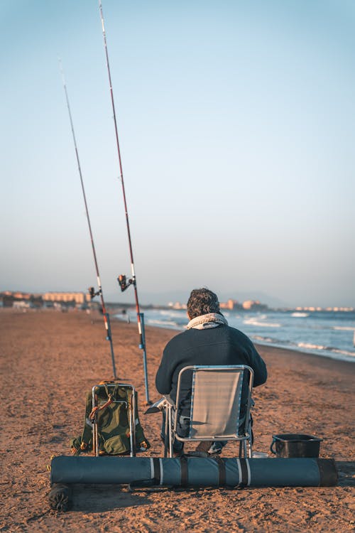 Man Sitting on a Chair on a Beach and Fishing · Free Stock Photo