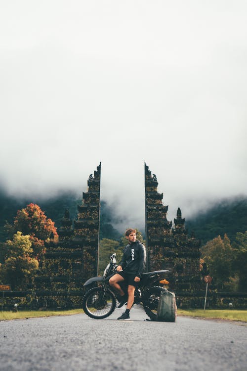 男子坐在塔附近的摩托車上的照片