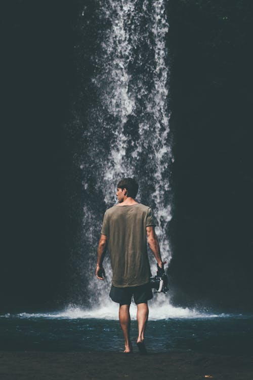 Человек в серой рубашке гуляет возле водопадов