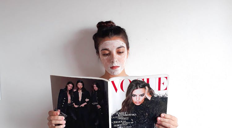 Woman With Cosmetic Mask Reading A Magazine