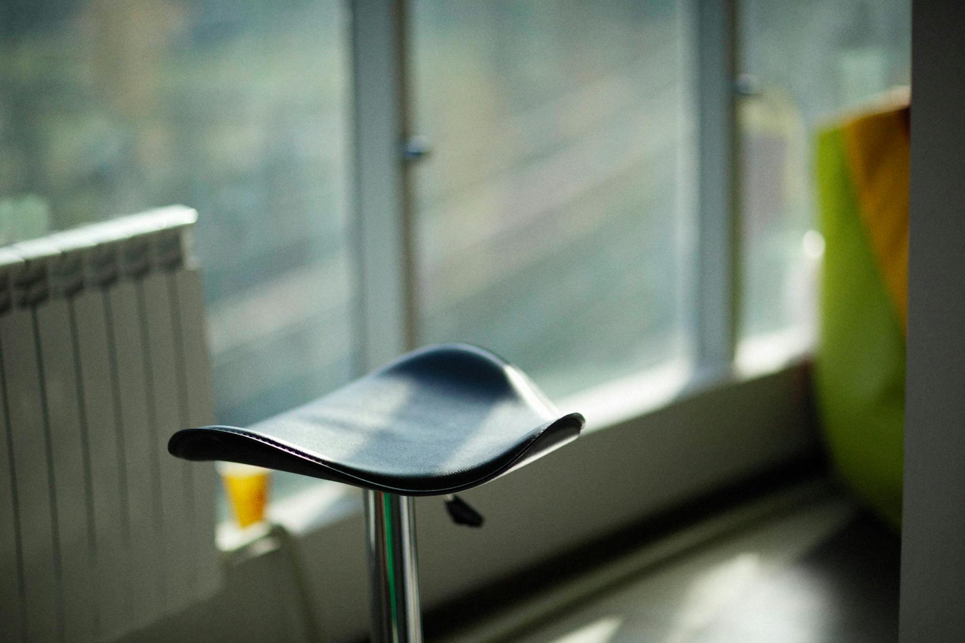 Stylish black bar stool with a hydraulic stand in a well-lit, modern interior.