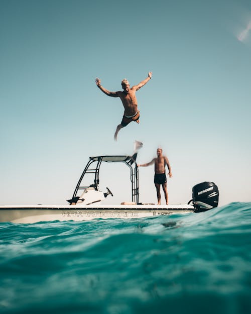 grátis Foto De Um Homem Saltando De Um Barco Para O Mar Foto profissional