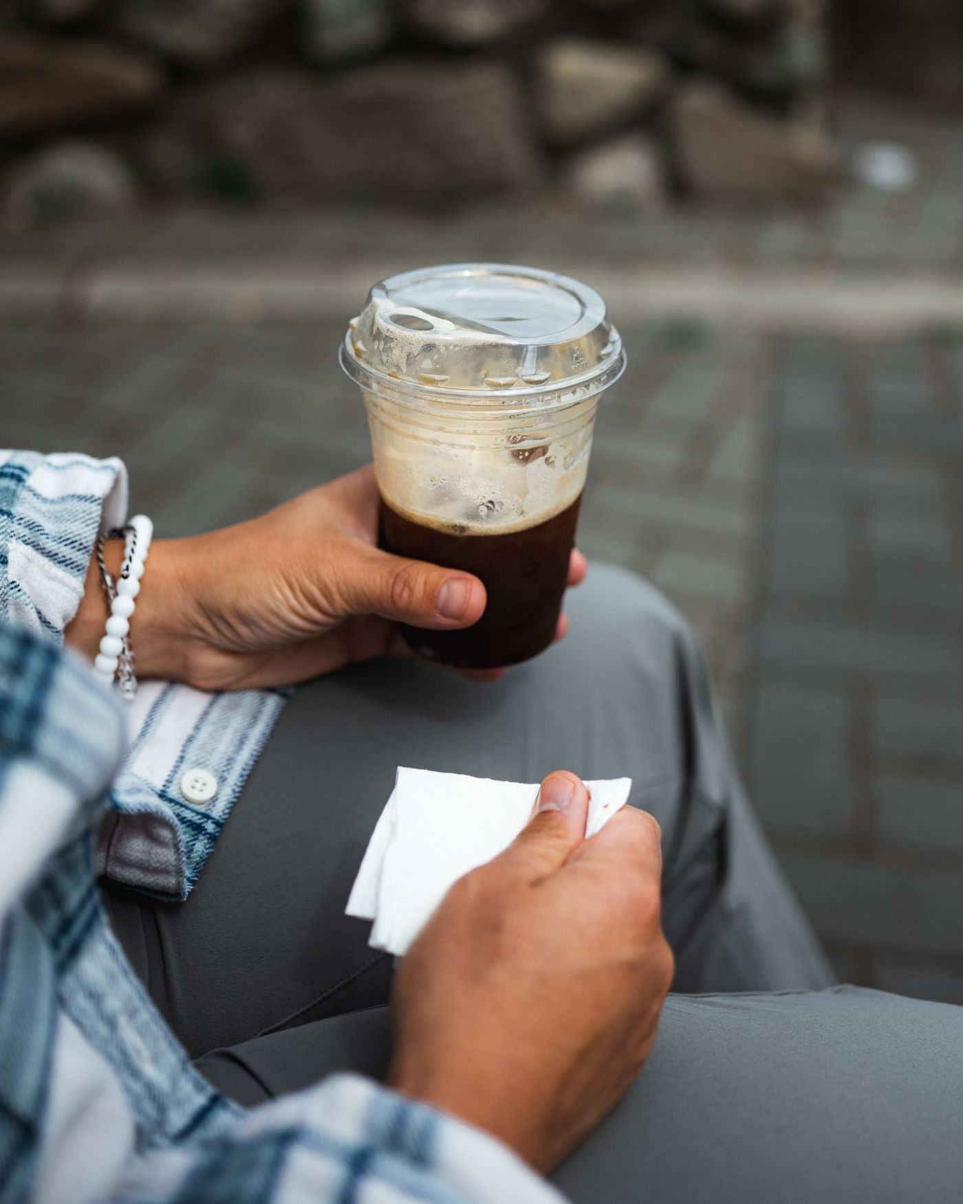 A person holding iced coffee outdoors