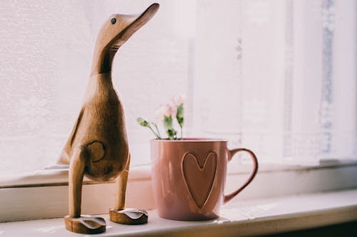 Brown Wooden Duck Figurine Near Brown Ceramic Mug