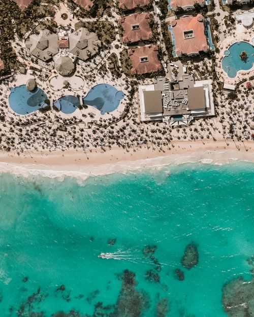 Free Aerial shot of a resort with turquoise waters, white sand beach, and luxurious pools. Stock Photo