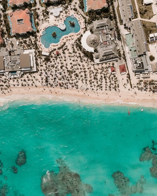 Free Stunning aerial shot of a beach resort with turquoise waters and lush palm trees. Stock Photo