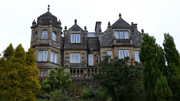 迷人的石头庄园与塔被郁郁葱葱的花园和树木包围