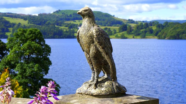 在明亮的天空下，鹰雕塑俯瞰着宁静的湖泊和郁郁葱葱的青山