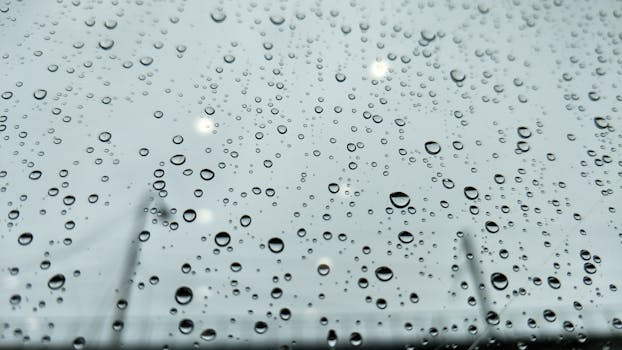 A detailed close-up of raindrops on a window glass during a rainy day in Chennai, India.
