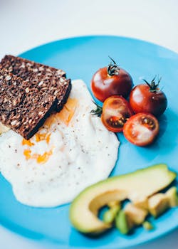 A nutritious breakfast plate featuring eggs, tomatoes, and avocado.