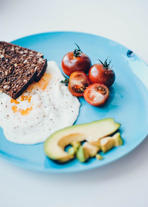 Free A vibrant and nutritious breakfast plate featuring avocado, sunny side up egg, whole grain toast, and ripe tomatoes. Stock Photo