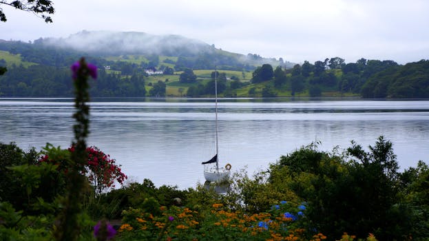 湖面风景如画，一艘帆船静静地停泊，四周环绕着鲜花和山丘