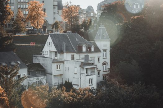 Scenic view of a European-style house nestled among autumn trees, capturing warm sunlight.