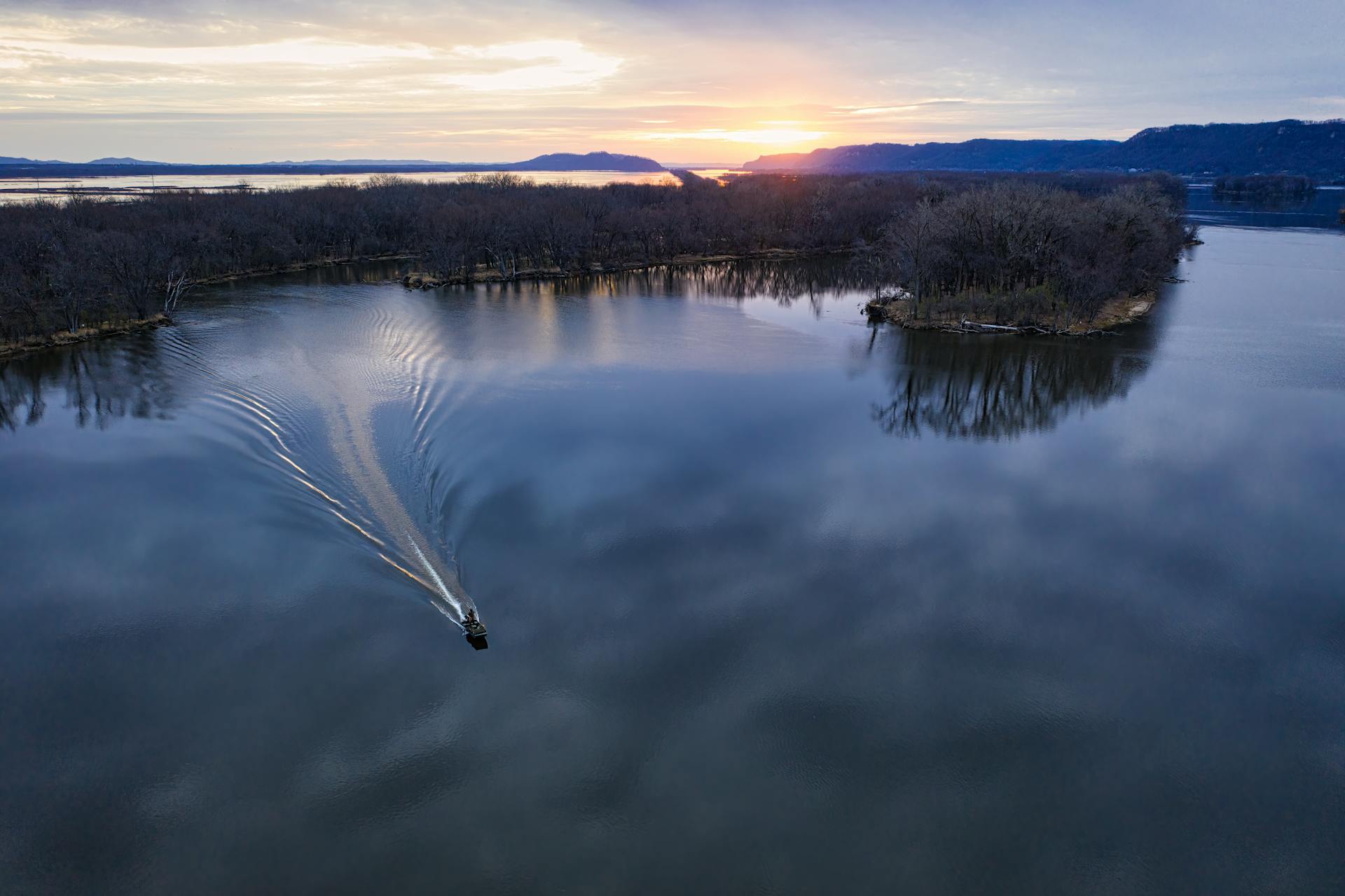 Aerial shot of a boat cruising Lake Winona with a beautiful sunset in the background.