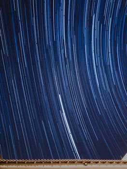 Mesmerizing long exposure photograph capturing curved star trails across a clear night sky.