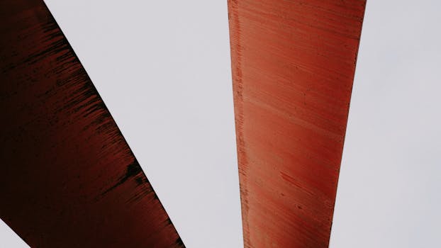 Close-up of abstract rusty metal structures against a light sky, providing a sense of geometric design.