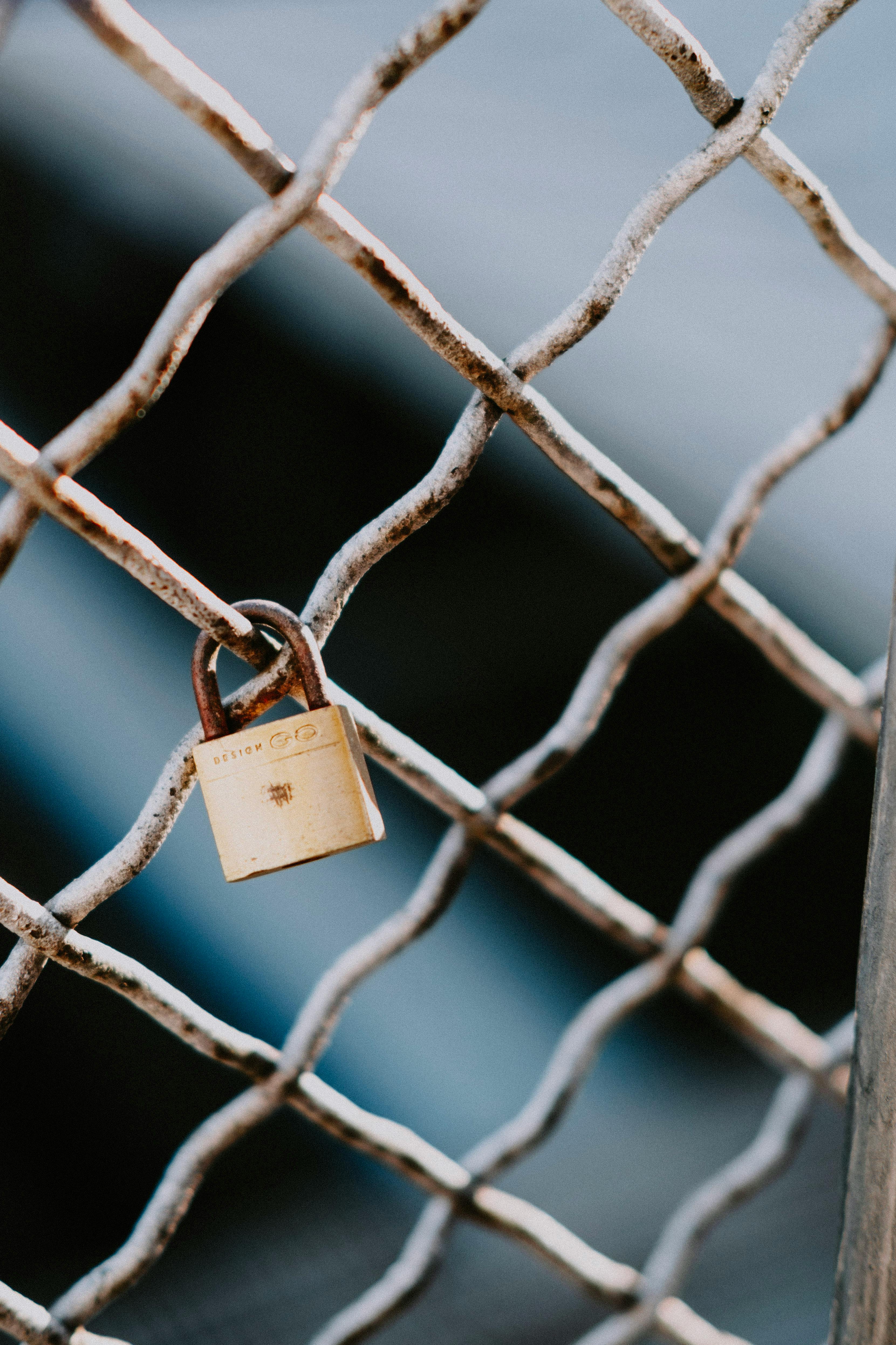 gold padlock on black metal fence