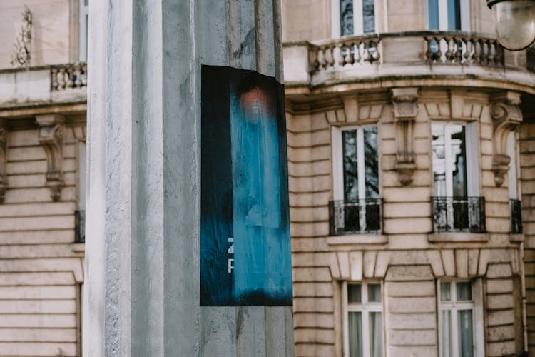 Close-up Of A Poster On A Pole In City And A Building In The Background 