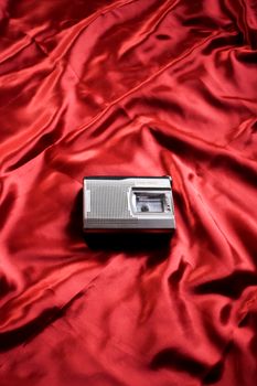 Vintage cassette player on red satin fabric, perfect for retro and nostalgic themes.