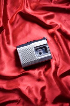 A vintage cassette player resting on luxurious red fabric in a top view layout.