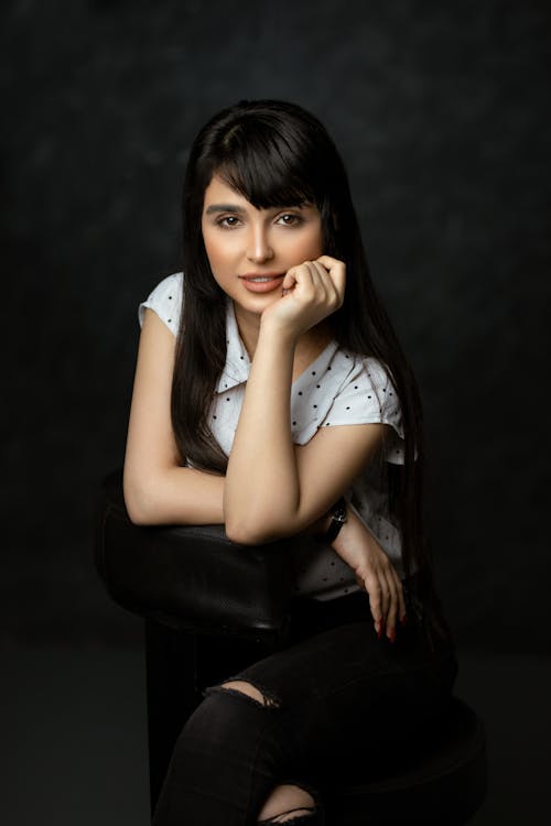 Free Woman in White Sleeveless Shirt Sitting on Black Leather Chair Stock Photo