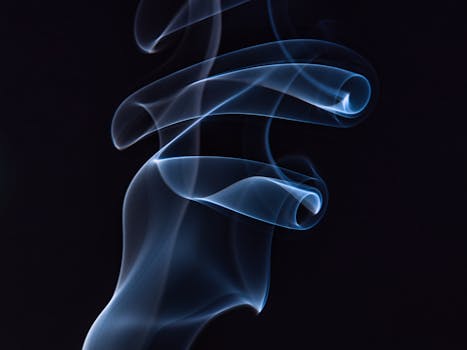 Artistic capture of swirling blue smoke against a black background, highlighting motion and elegance.