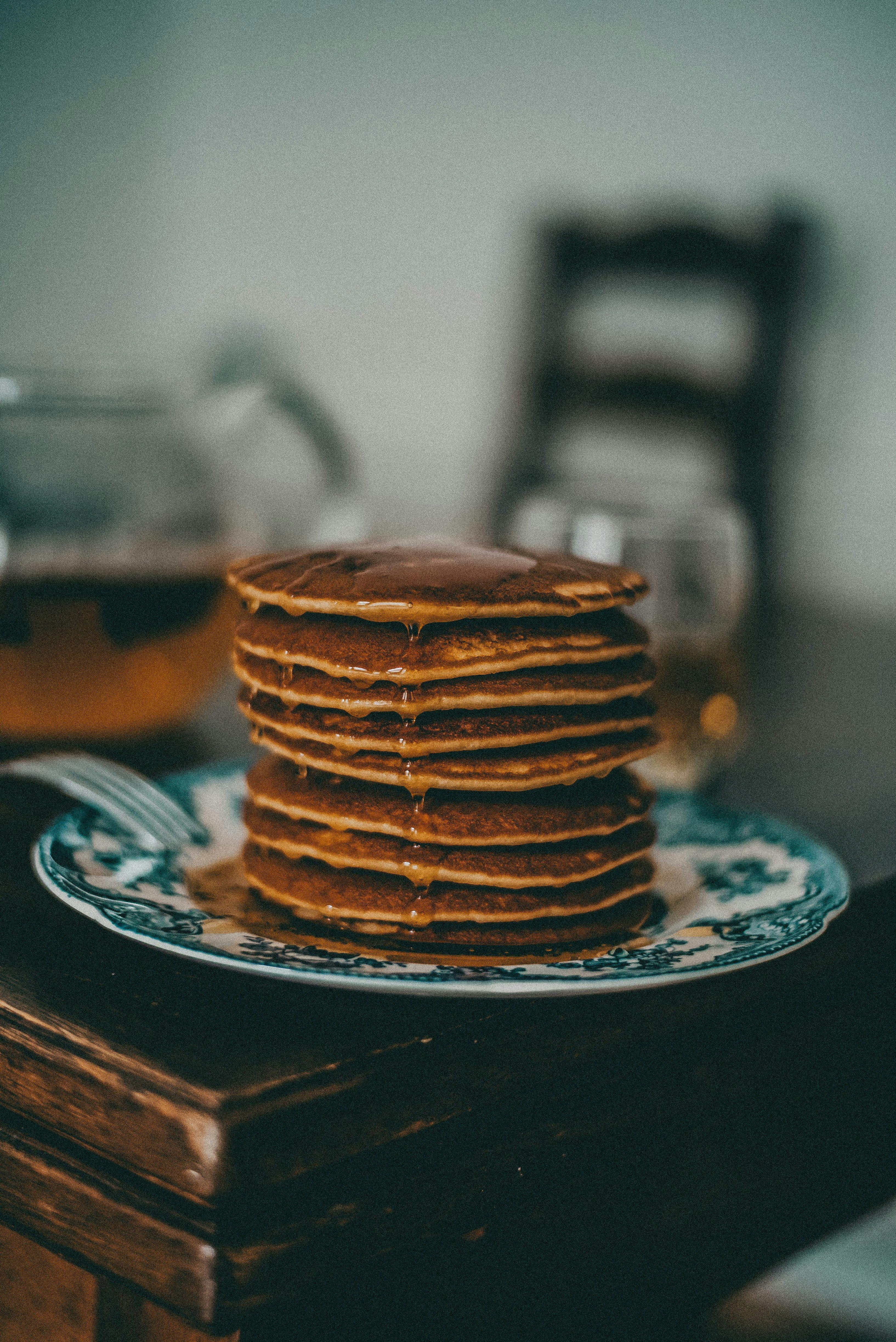 Mouth-watering stack of pancakes with syrup on a rustic dining table. Perfect breakfast scene.