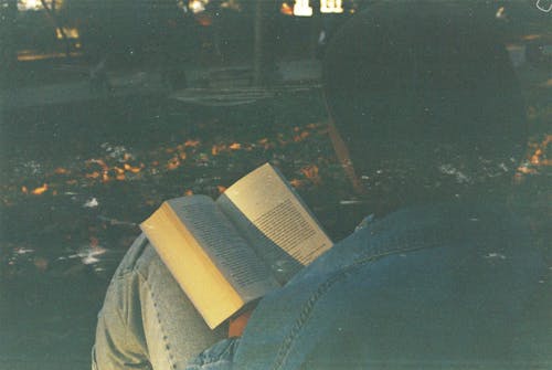 Person in Blue Denim Jeans Reading a Book