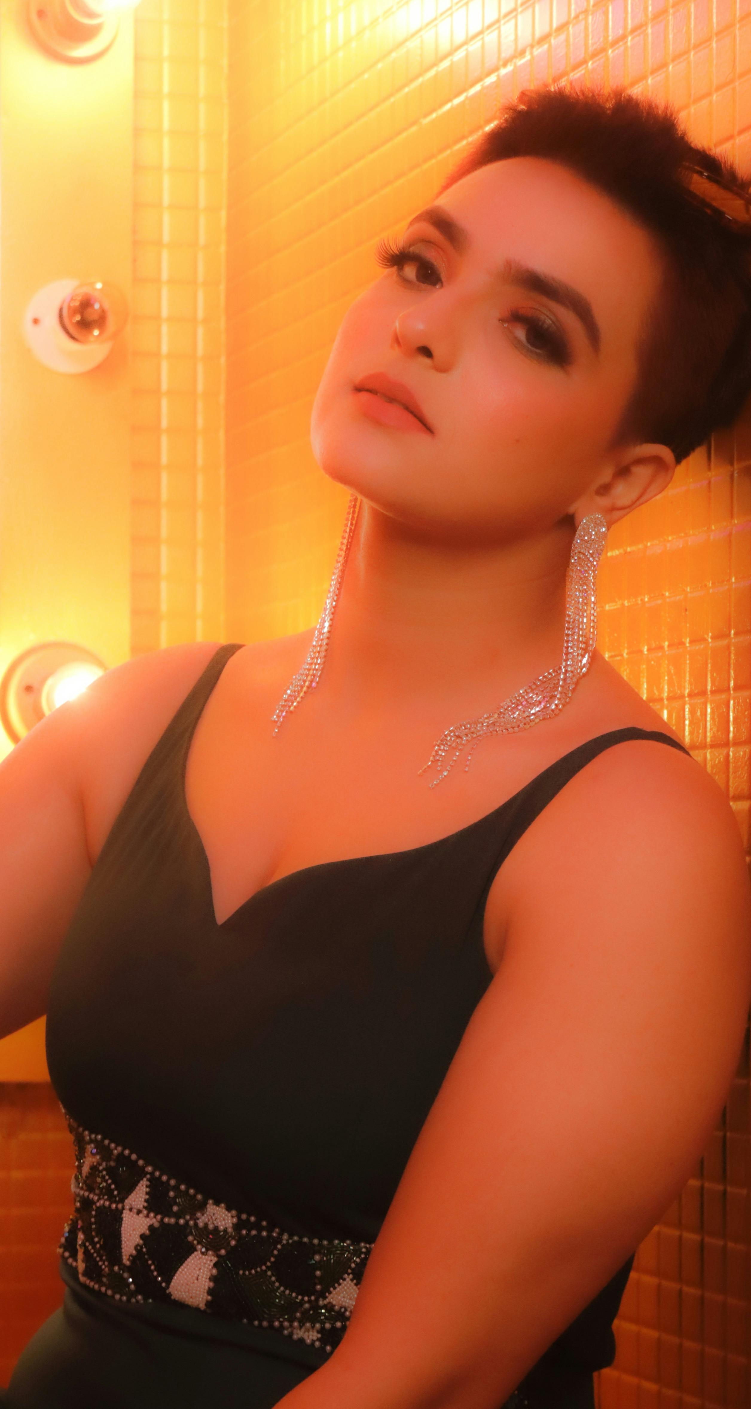 Striking portrait of a woman in elegant attire against warm lit background.