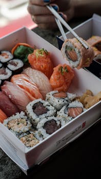 Close-up of an appetizing sushi platter with chopsticks, showcasing a variety of Japanese rolls.