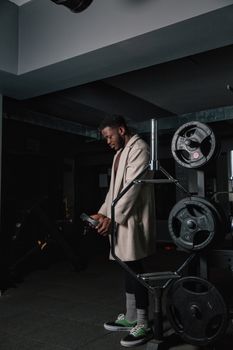 African American man in a gym holding weights, dressed casually, indoor setting.
