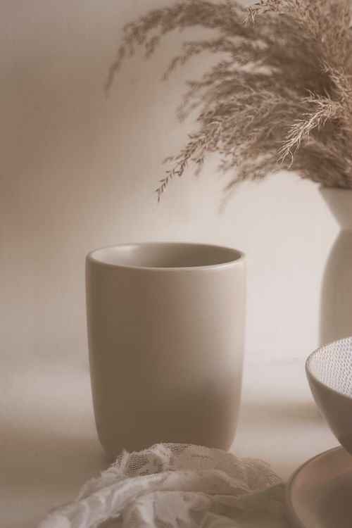 Free A minimalist ceramic cup paired with dried flowers on a neutral background. Stock Photo