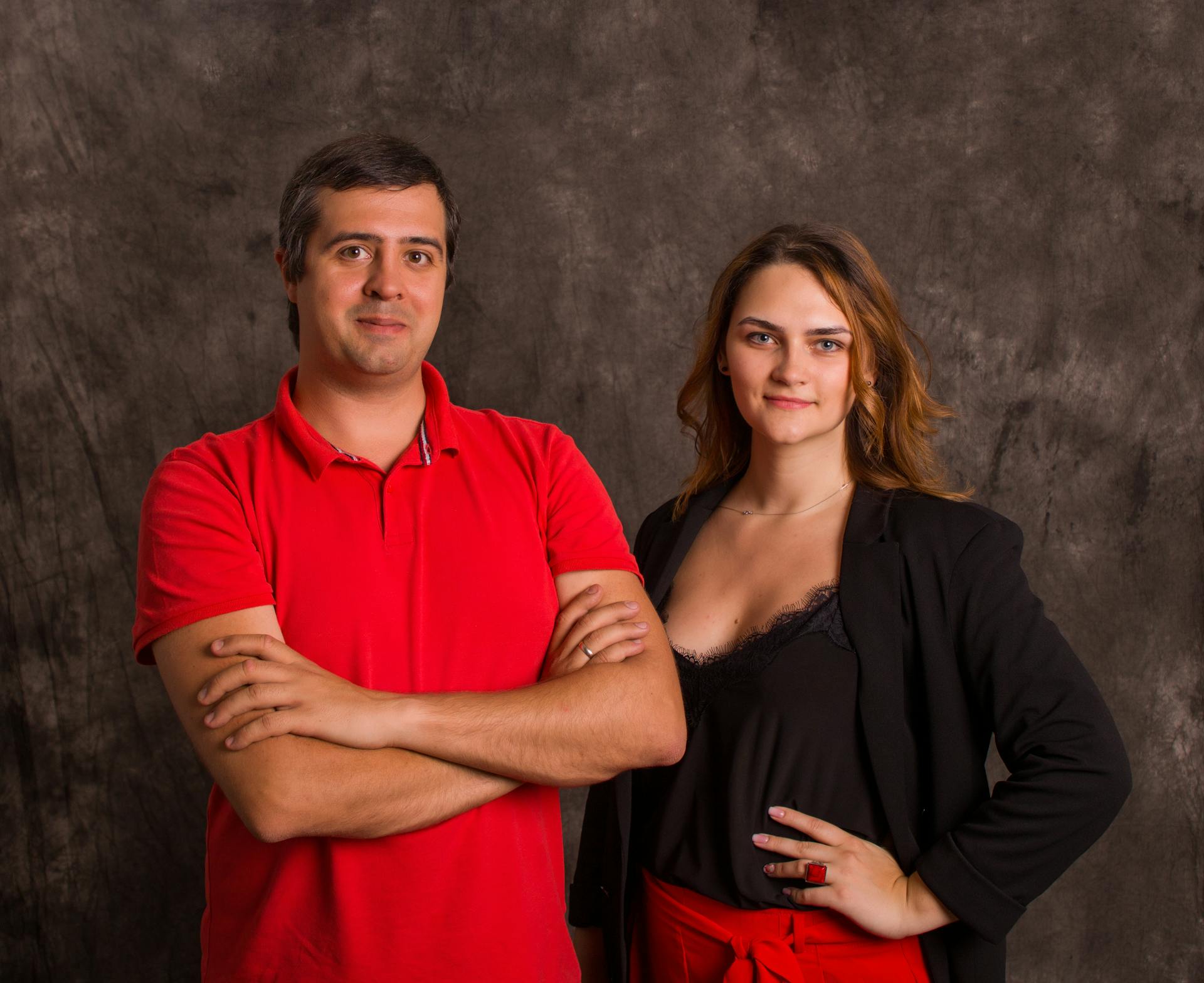 Studio portrait of a confident man and woman in business attire posing in front of a textured backdrop.