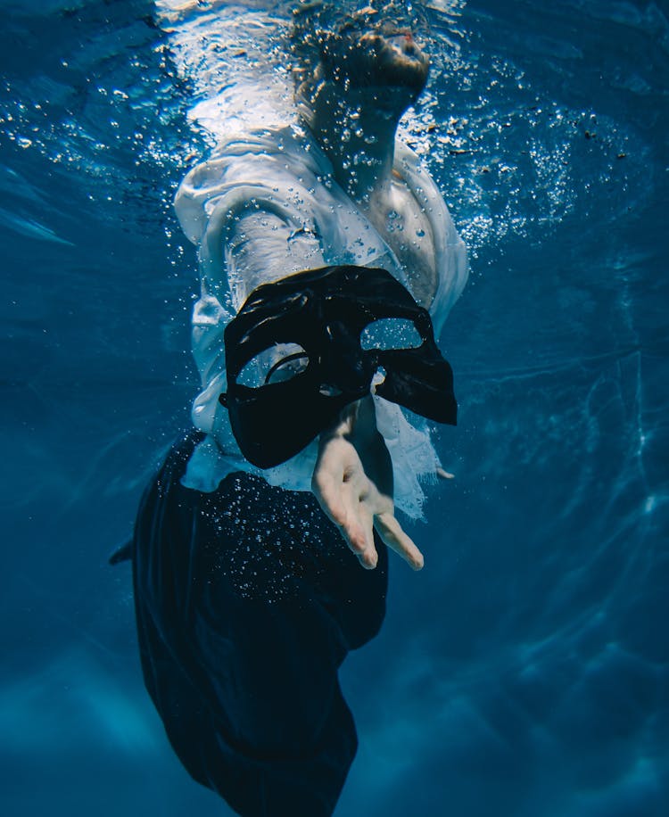 A Person's Hand Reaching For A Mask Underwater