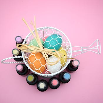 Top view of colorful eggs in net basket with a pink background, surrounded by vials, perfect for Easter themes.