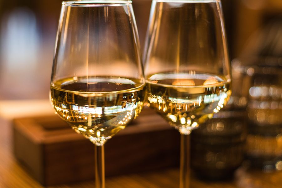 Two glasses of white wine in warm light, illustrating the wine market that Corticeira Amorim's cork stoppers serve