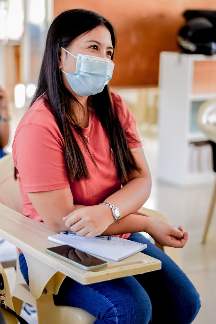 A Student Sitting With A Face Mask On