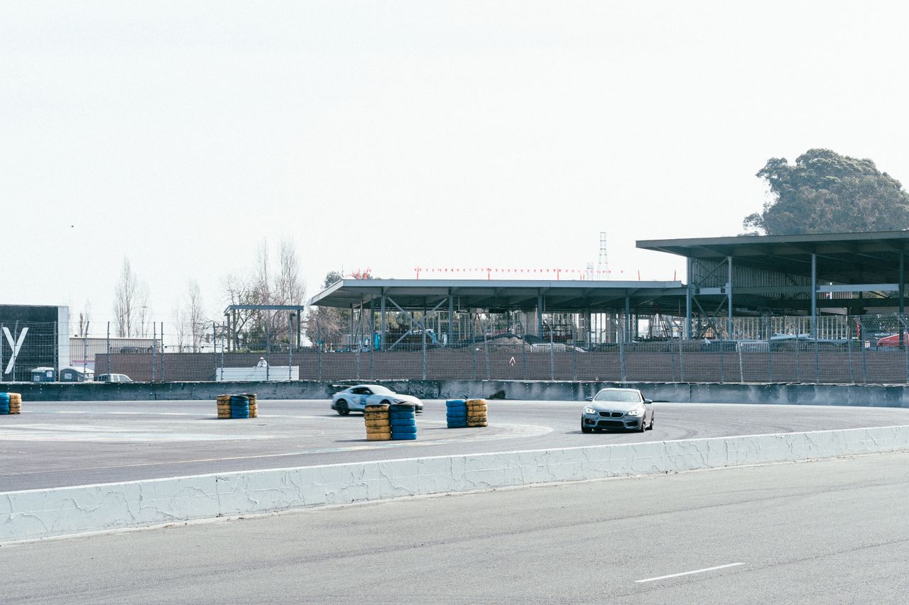 cars racing on an urban track with empty stands and a clear sky