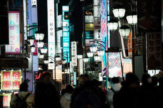 Bustling street scene in Shinjuku, Tokyo capturing vibrant signs and evening crowds.