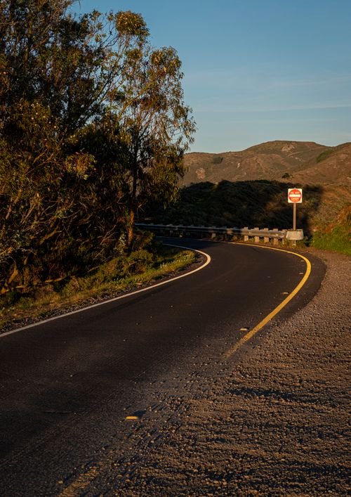 Free A winding asphalt road in the countryside during a serene golden hour. Stock Photo
