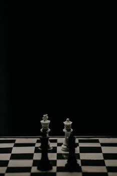 Artistic monochrome view of a chessboard highlighting strategic game pieces in focus.