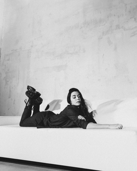 A monochrome photo of a woman in boots lying on a couch, exuding a relaxed and stylish vibe.
