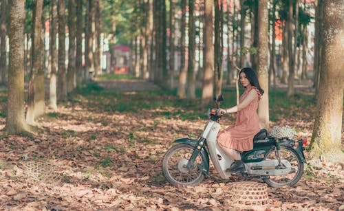 Free Woman Riding Underbone Motorcycle Between Trees Stock Photo