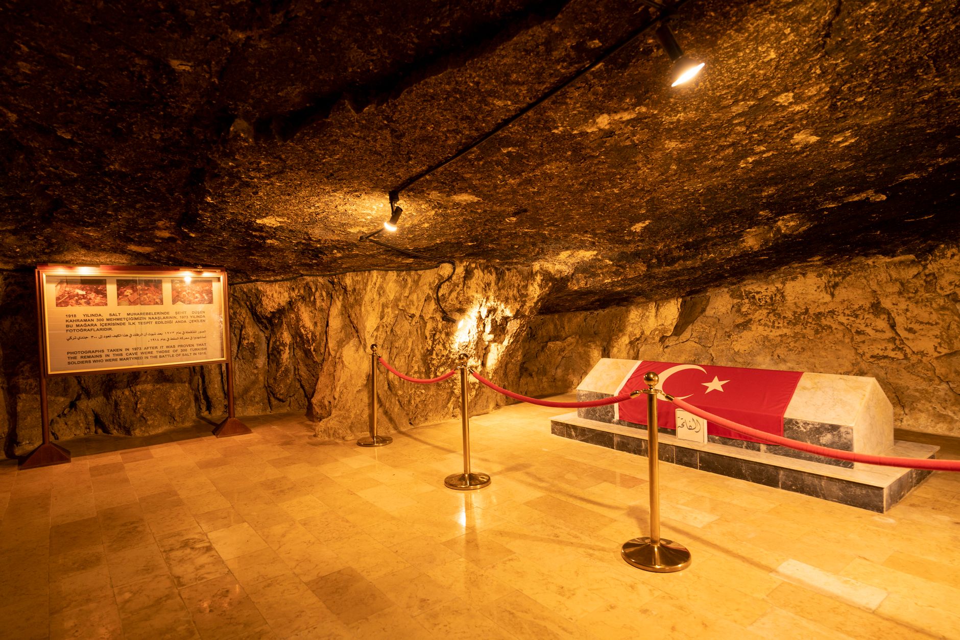 An underground tomb with a Turkish flag inside a rocky cave illuminated with warm lighting.