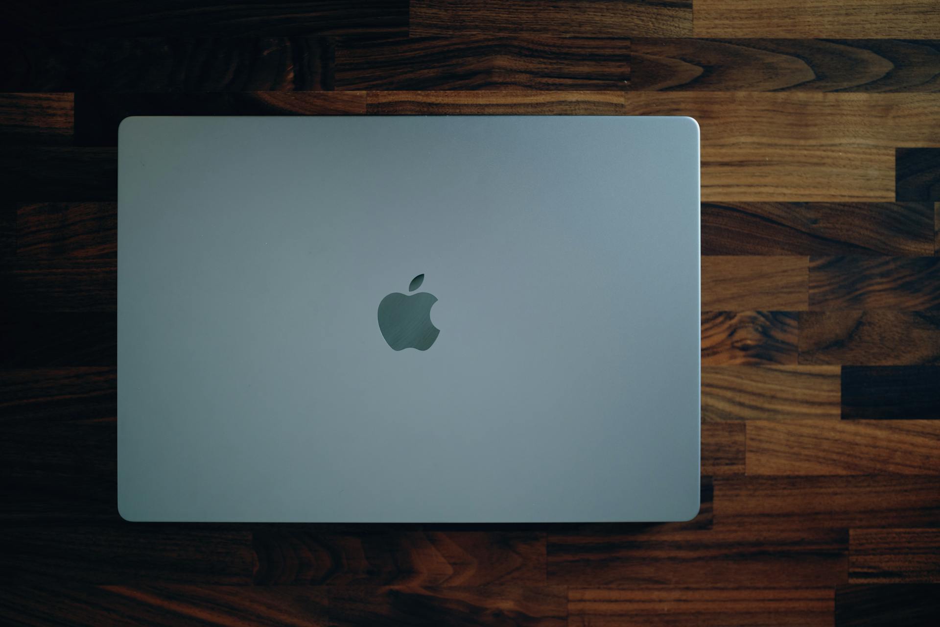 Sleek MacBook closed on a rich wooden surface, highlighting its minimalist design and modern technology.