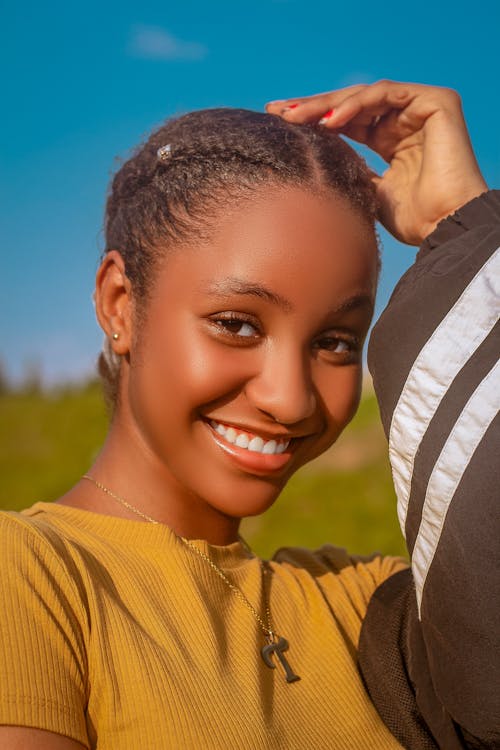 A Smiling Woman in Yellow Shirt Holding Her Hair