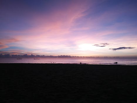 A calming beach sunset with silhouettes and vibrant sky colors.