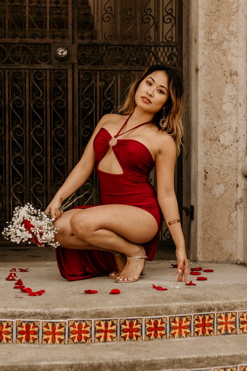 Free Woman in Sexy Red Dress Crouching in Circle From Rose Petals  Stock Photo