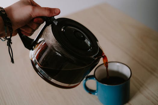 Close-up of coffee being poured into a blue mug, showcasing a moment of caffeine preparation.