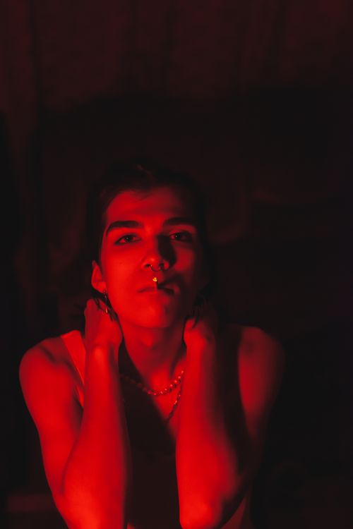 Free Dramatic portrait of an adult with red lighting, smoking with hands behind head. Stock Photo